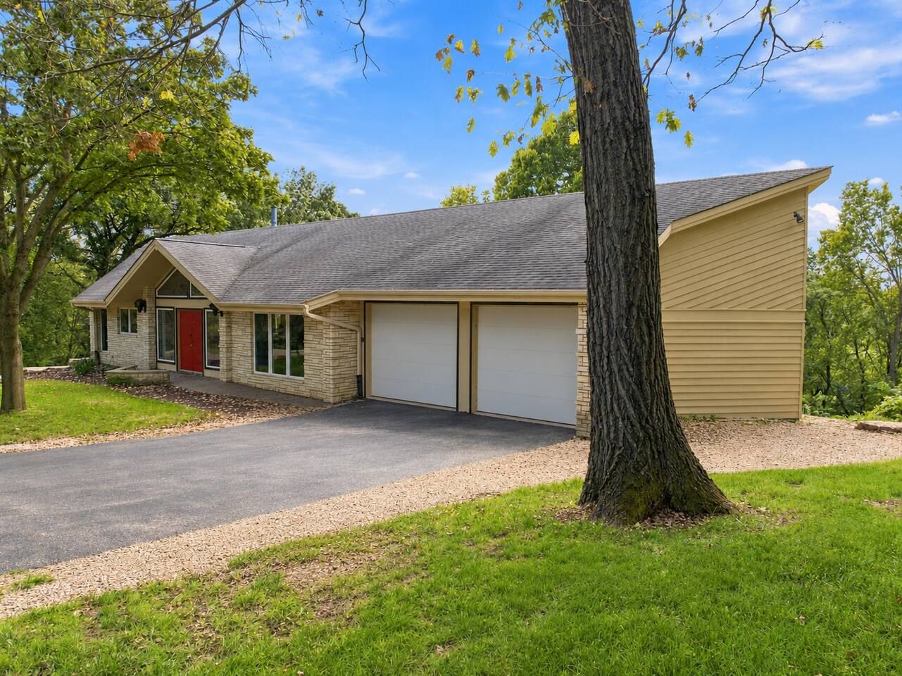 A two-story building with a garage, a red door, and a driveway.