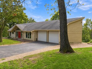 A two-story building with a garage, a red door, and a driveway.