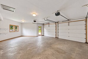Un garage spacieux doté d’un sol en béton, d’une grande porte de garage et d’un projecteur fixé au plafond.