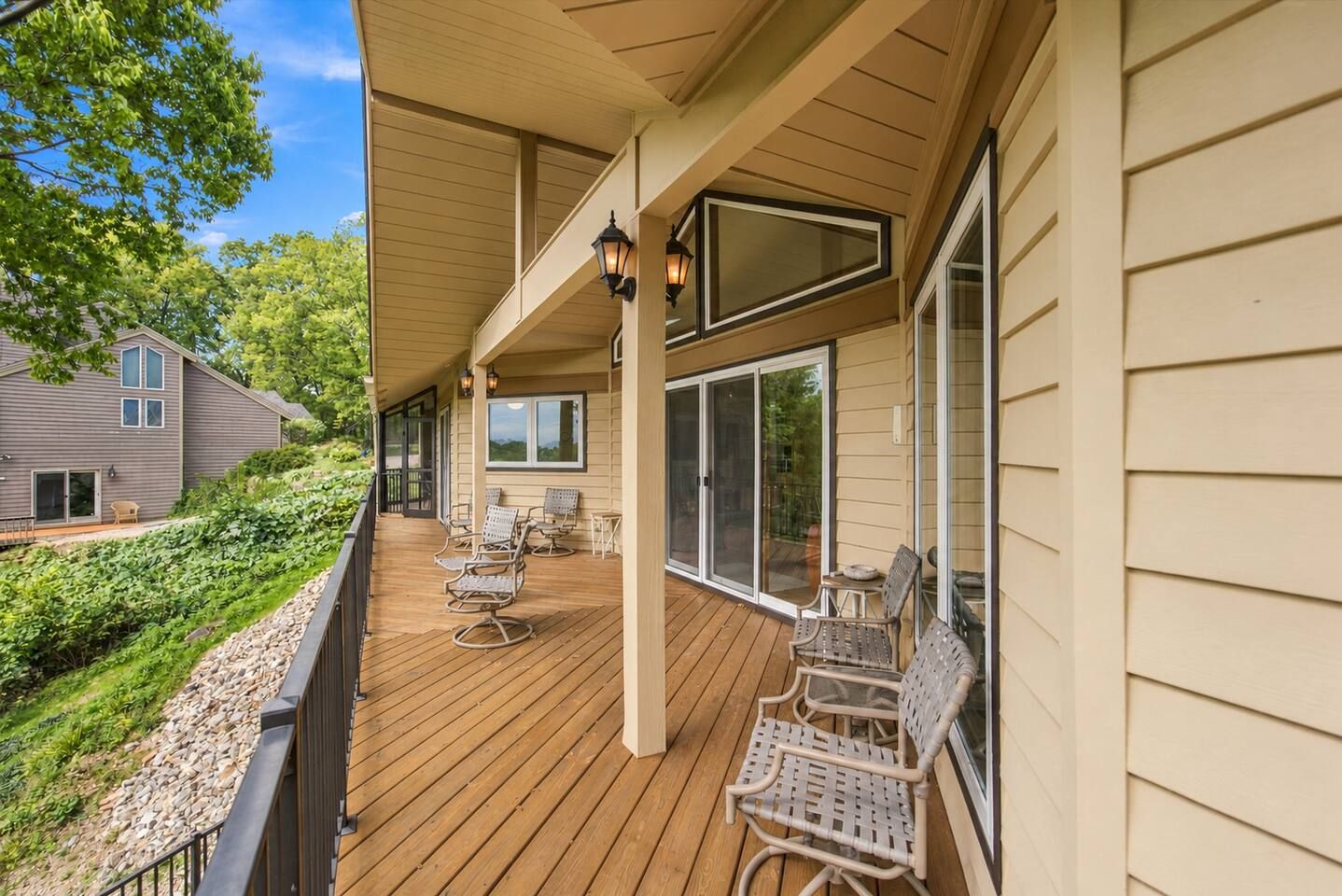 A wooden deck with outdoor furniture and a covered area with windows.
