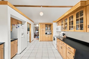 A kitchen with wooden cabinets, a refrigerator, a microwave, and a stove. - The Architect’s Overlook | Sweeping Valley Views (Galena)