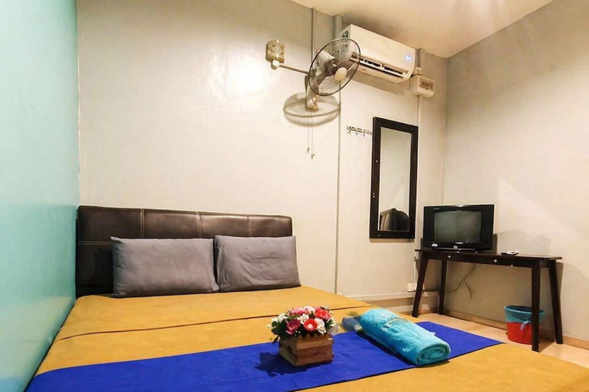 A hotel room with a bed, a television, a small table, and a mirror.