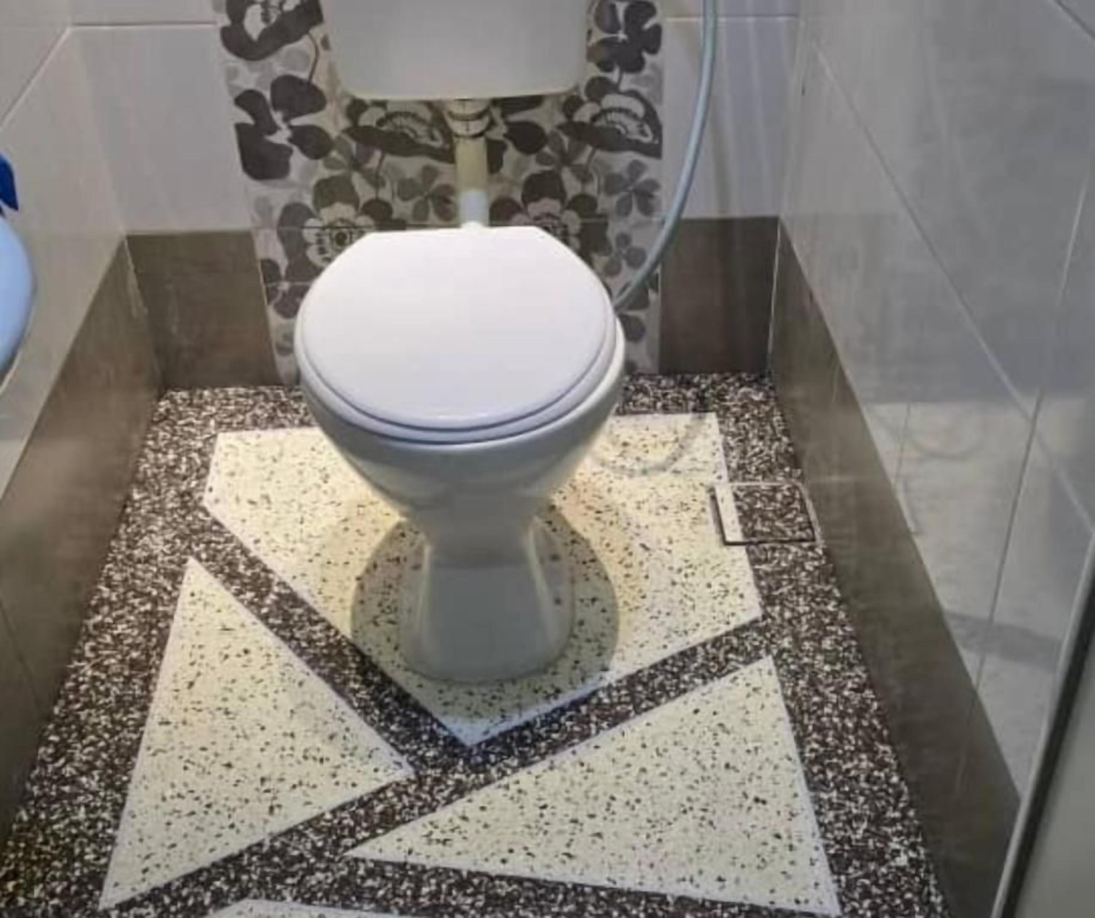 A toilet with a white seat and lid, positioned on a speckled floor with directional arrows.