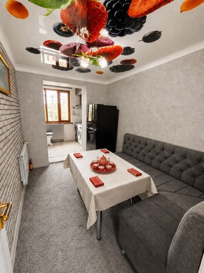 A modern kitchen with a dining area, a grey sofa, and a table set for four. - Tranquil 2-bedroom apartment with AC in charming Samarqand (Samarqand)