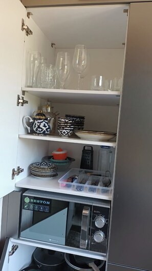 A kitchen with a microwave, shelves with glassware, and a coffee maker. - Tranquil 2-bedroom apartment with AC in charming Samarqand (Samarqand)