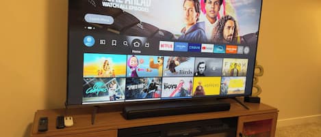 A flat-screen TV on a wooden entertainment center with a fireplace below it.