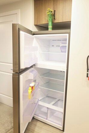 A kitchen with a stainless steel refrigerator, a wooden cabinet above it, and a vase with flowers on the cabinet. - Luxury Private Suite, Near Calgary Airport (Calgary)