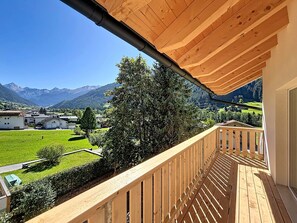 A wooden balcony with a view of a green landscape and mountains in the distance. - Apartment Inari by Interhome (Gortipohl)