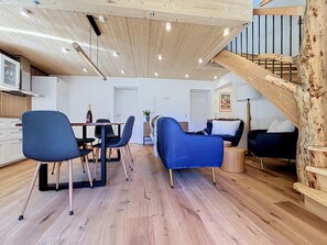 A modern interior with a dining area, seating, and a wooden staircase. - Apartment Inari by Interhome (Gortipohl)