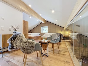 A modern interior with a loft-style bedroom, wooden flooring, and a glass railing overlooking a balcony. - Apartment Akira by Interhome (Gortipohl)