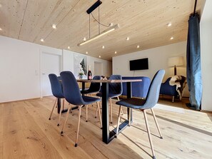 A modern dining area with a wooden ceiling, a flat-screen TV, and a table with chairs. - Apartment Laika by Interhome (Gortipohl)