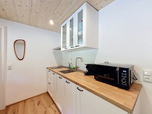 Una cucina compatta con un piano di lavoro in legno, un lavello, pensili e un forno a microonde.