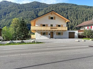 Ein zweistöckiges Gebäude mit Balkon, Holzfassade und Bergblick.