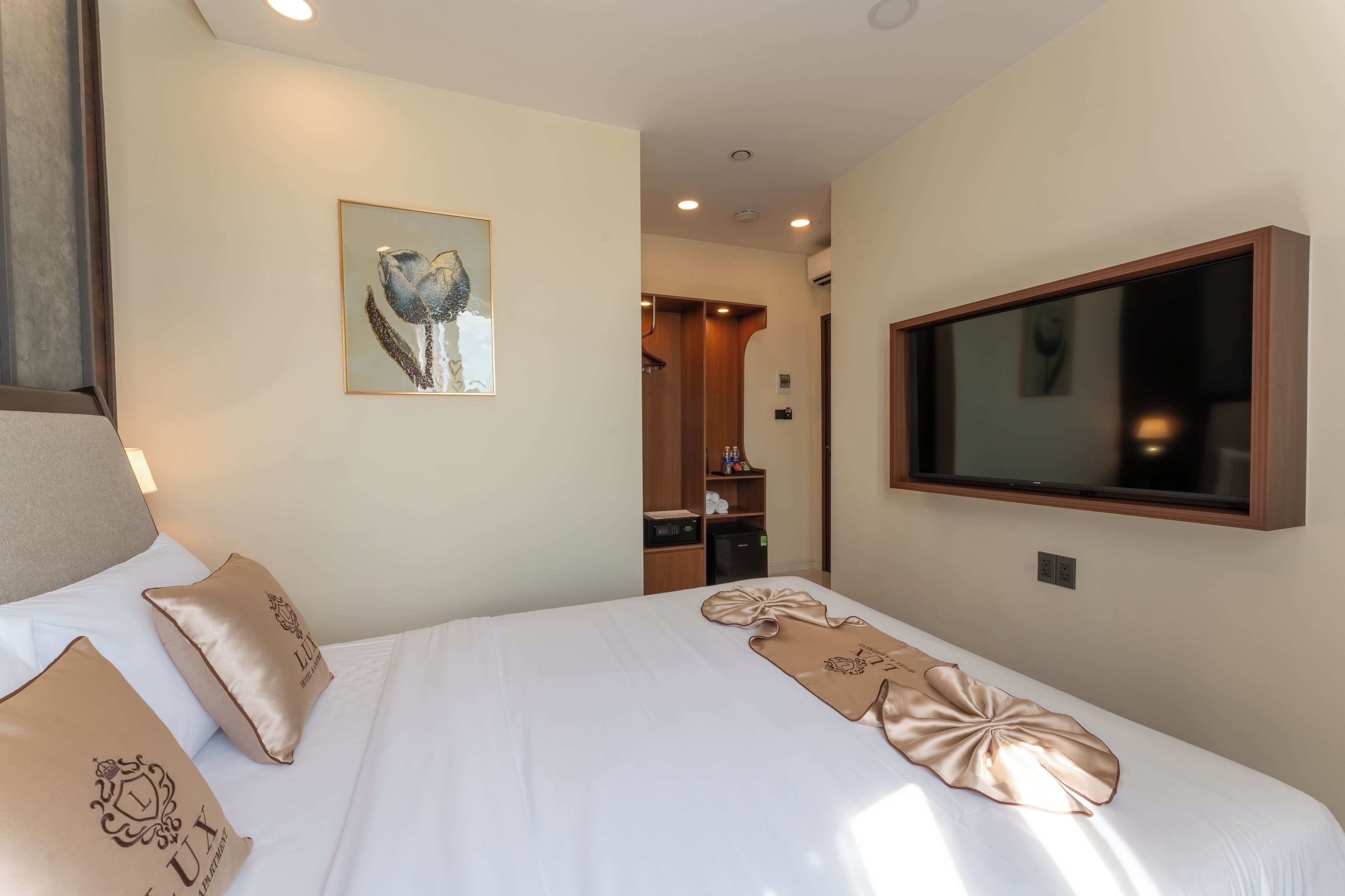 Une chambre d’hôtel avec un lit, une télévision, un tableau au mur et un minibar.