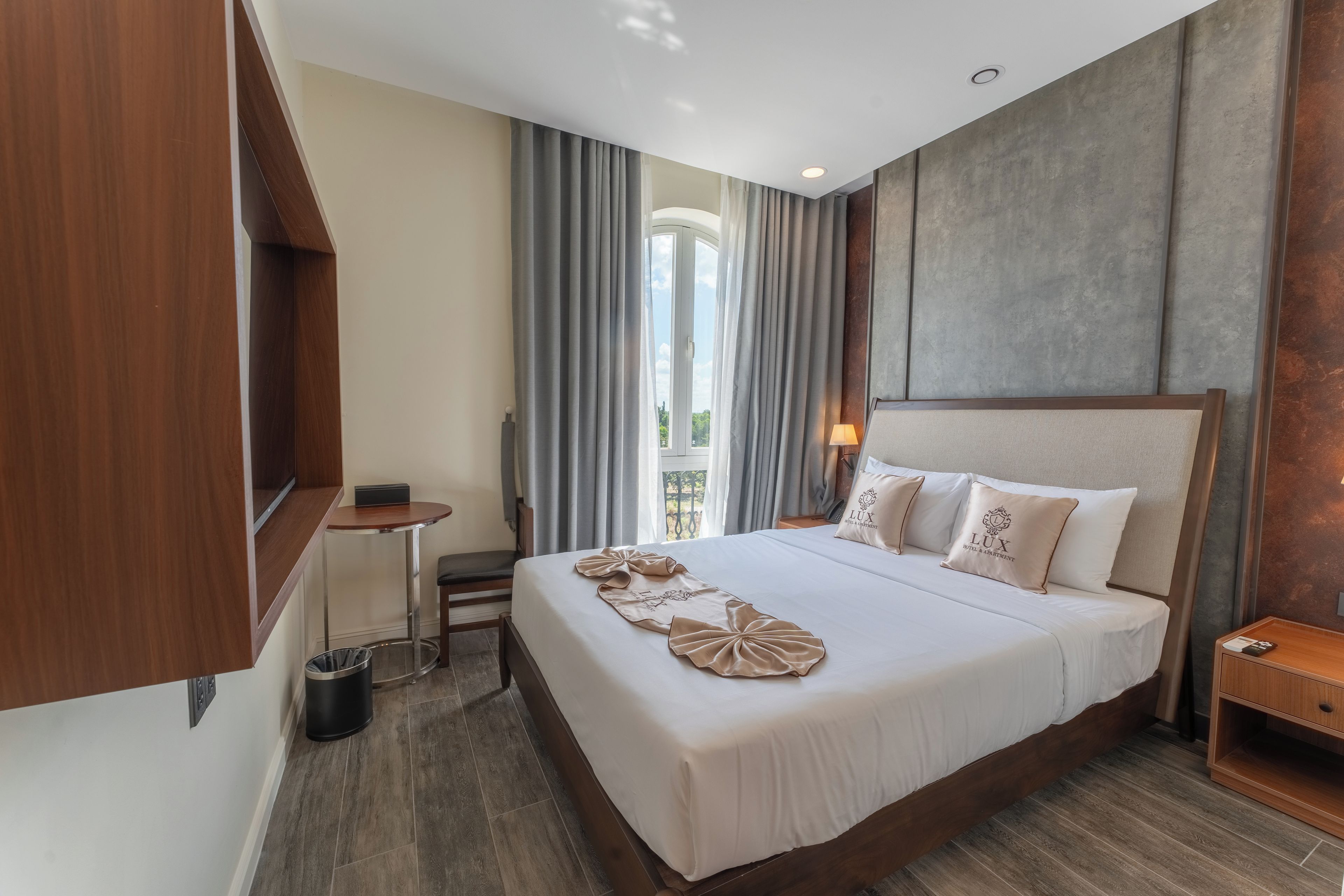 Habitación de hotel con una cama grande, una mesita, una silla, un cubo de basura y vistas al exterior.
