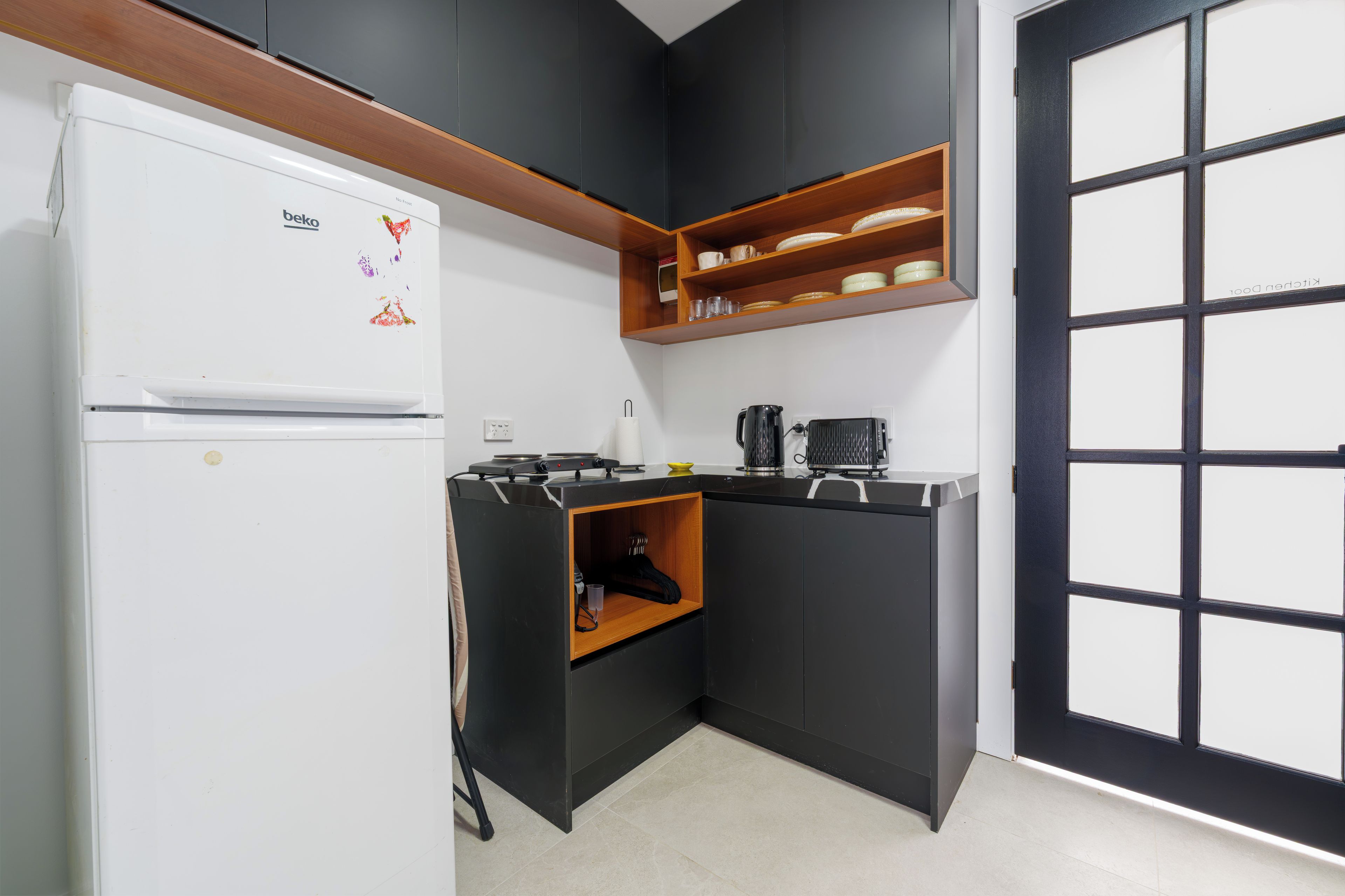 Una cucina compatta con frigorifero bianco, fornello e macchina da caffè.