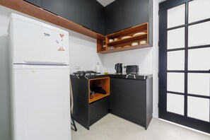 A compact kitchen with a white refrigerator, a stove, and a coffee maker.