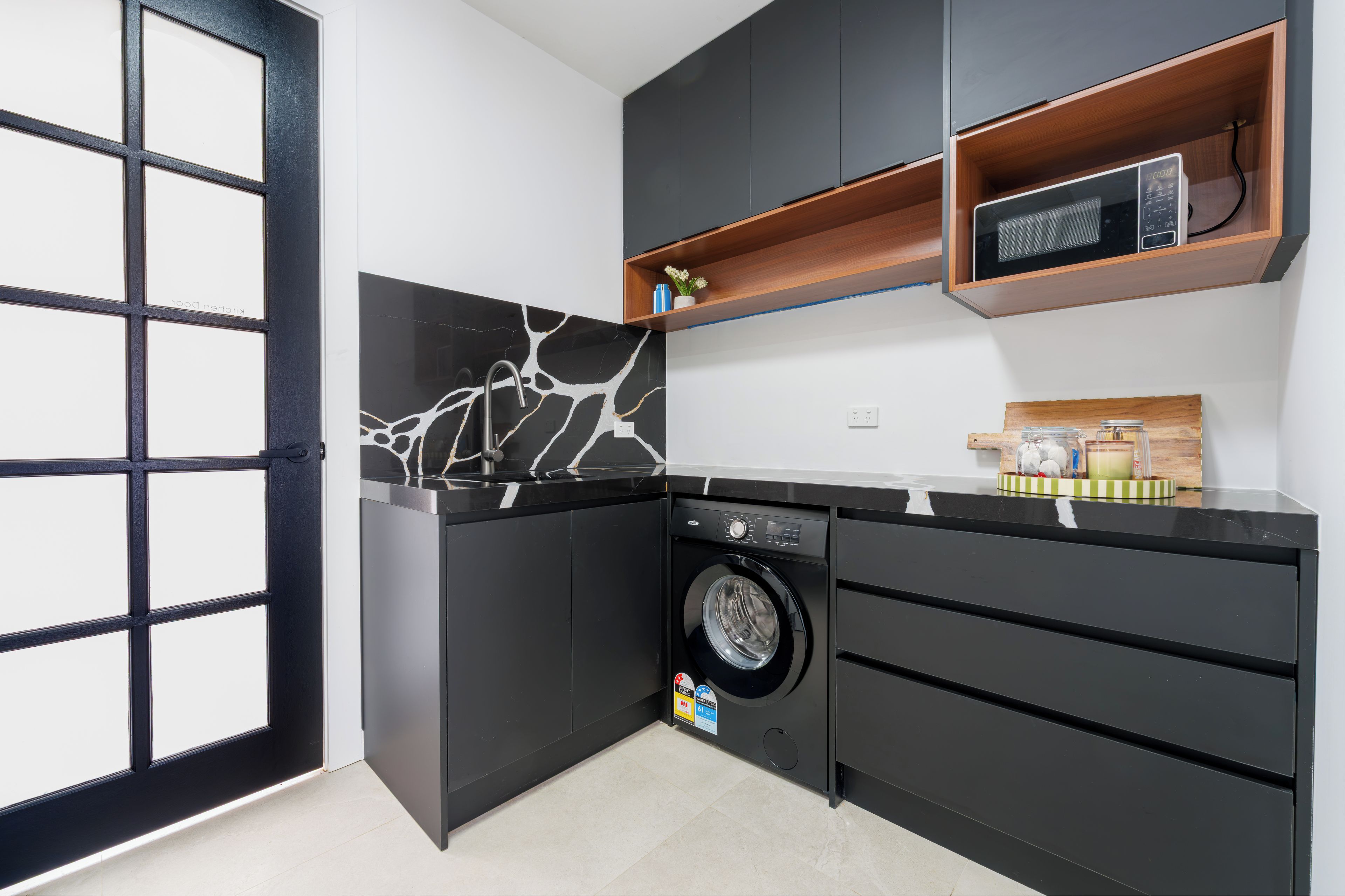 Stylish modern kitchenette with laundry, sleek finishes, and smart storage