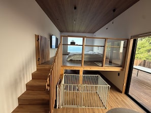 Un dormitori modern amb sostre de fusta, un llit superposat i vistes a l'exterior.