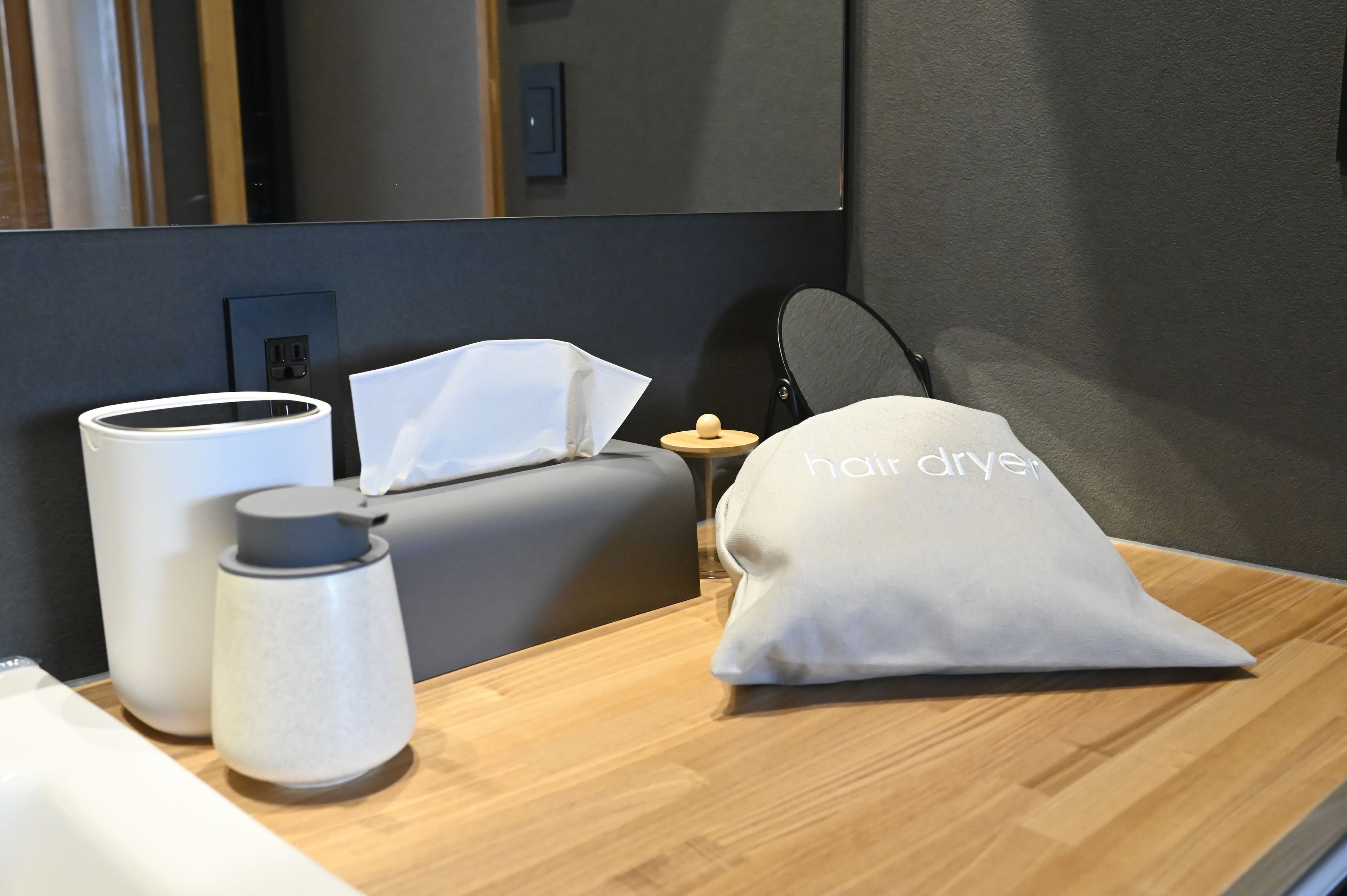 Ein Hotelzimmer mit Nachttisch, Haartrockner, Taschentuchbox und Wasserflasche.