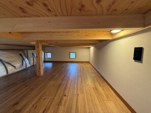 Un amplio ático con vigas de madera, techo inclinado y un ventanal grande.