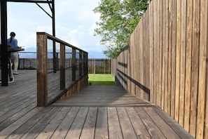 A wooden deck leading to a grassy area with a view of the mountains. - MORI｜Private Villa with a Dog Run (Suwa-shi)