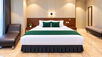 A modern hotel room with a large bed, a wooden headboard, a bedside table with a plant, a bench, and a large mirror.