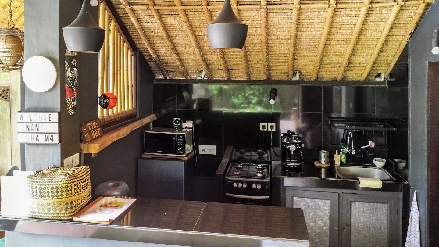 Une cuisine avec un plafond en bambou, un four à micro-ondes, une cuisinière et un évier.