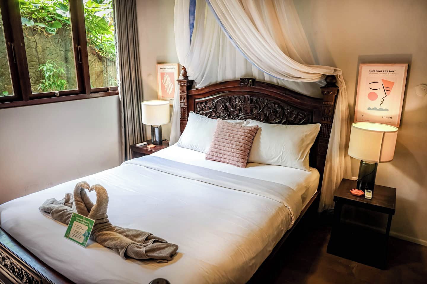 A neatly made bed with a white bedspread, a decorative headboard, and a pair of towels on the side.
