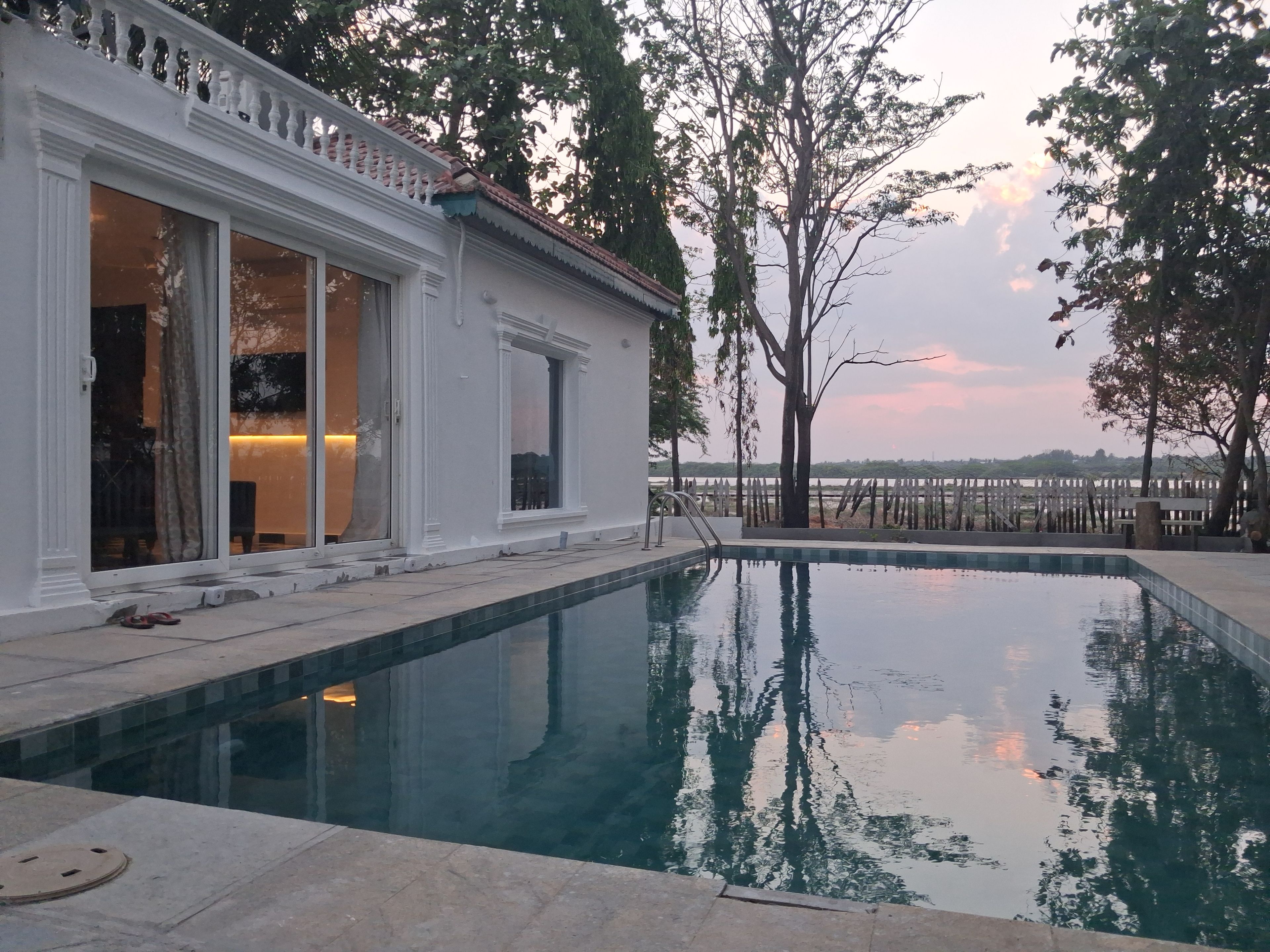 A swimming pool adjacent to a building with large windows and a view of the water.