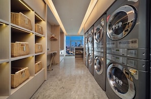 A laundry facility with multiple washing machines and wicker baskets on shelves. - YING'nFlO BY LANGHAM CHANGSHA (Changsha)