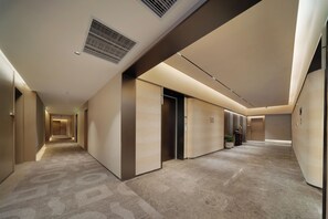 A hotel corridor with a carpeted floor, doors, and a vent on the ceiling. - YING'nFlO BY LANGHAM CHANGSHA (Changsha)