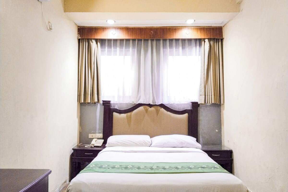 A hotel room with a bed, bedside tables, a telephone, and curtains.