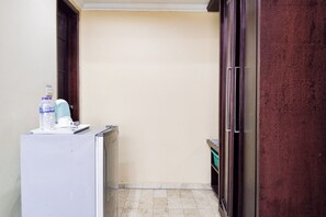 A narrow corridor with a white refrigerator, a water dispenser, and a small table. - SNUZ Hotel Menteng (Jakarta)