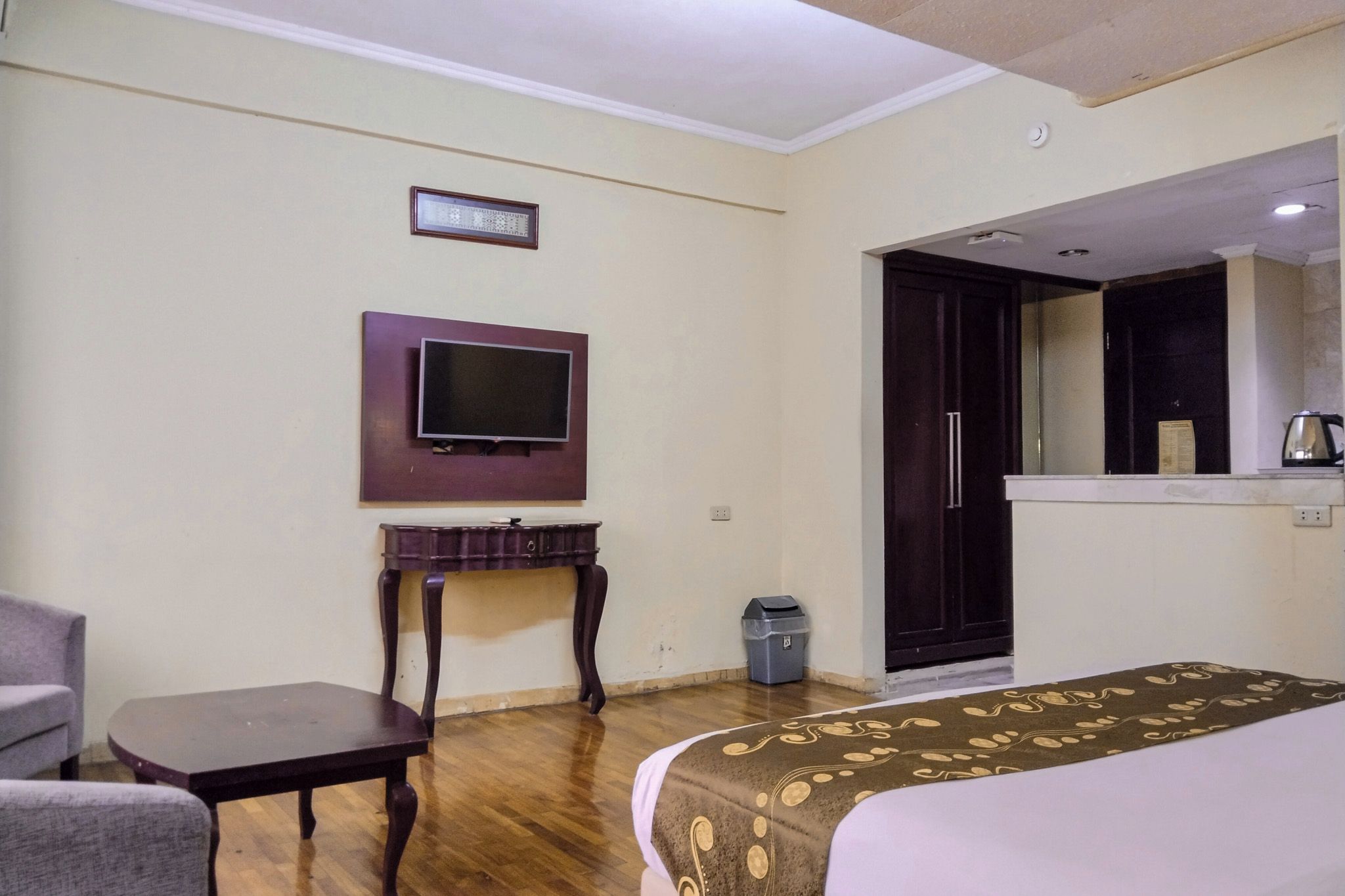 A hotel room with a bed, a television mounted on the wall, a small table, and a chair.