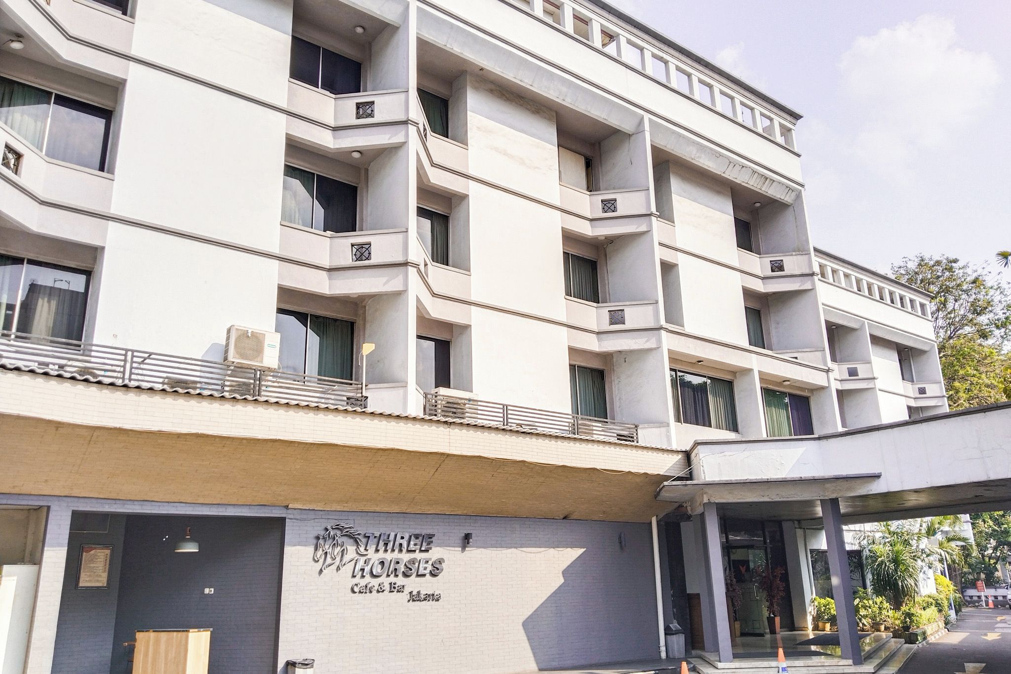 A multi-story building with a cafe and bar named 'THREE HORSES' on the ground floor.