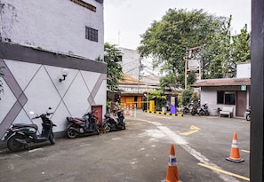 Vista de la calle con scooters estacionados, una oficina de seguridad y un edificio con fachada de azulejos.