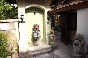 A courtyard with a statue of a deity, a small shrine, and a sign indicating CCTV surveillance.