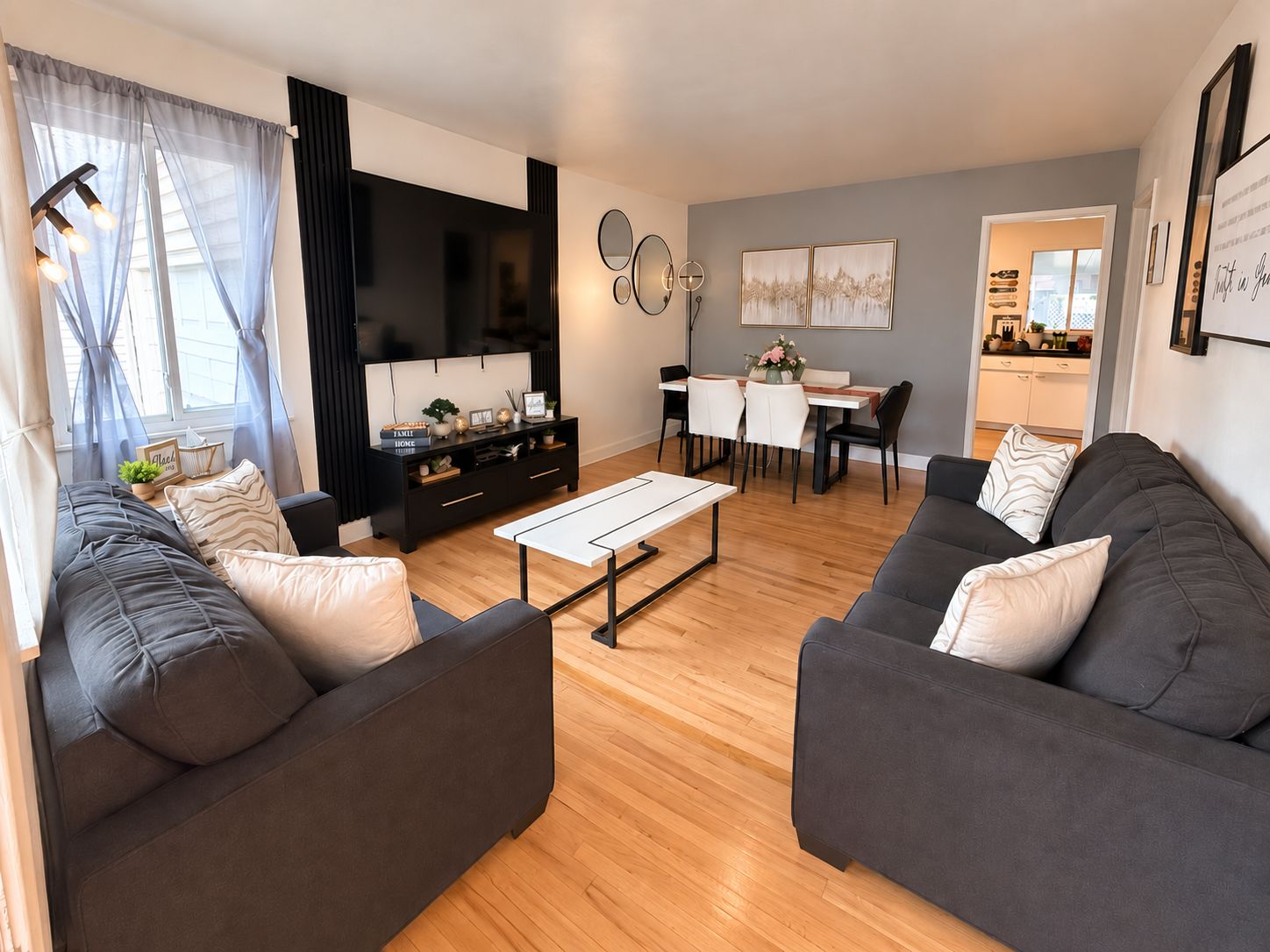 A modern living room with a sofa set, a coffee table, a TV, and a dining area with chairs and a table.