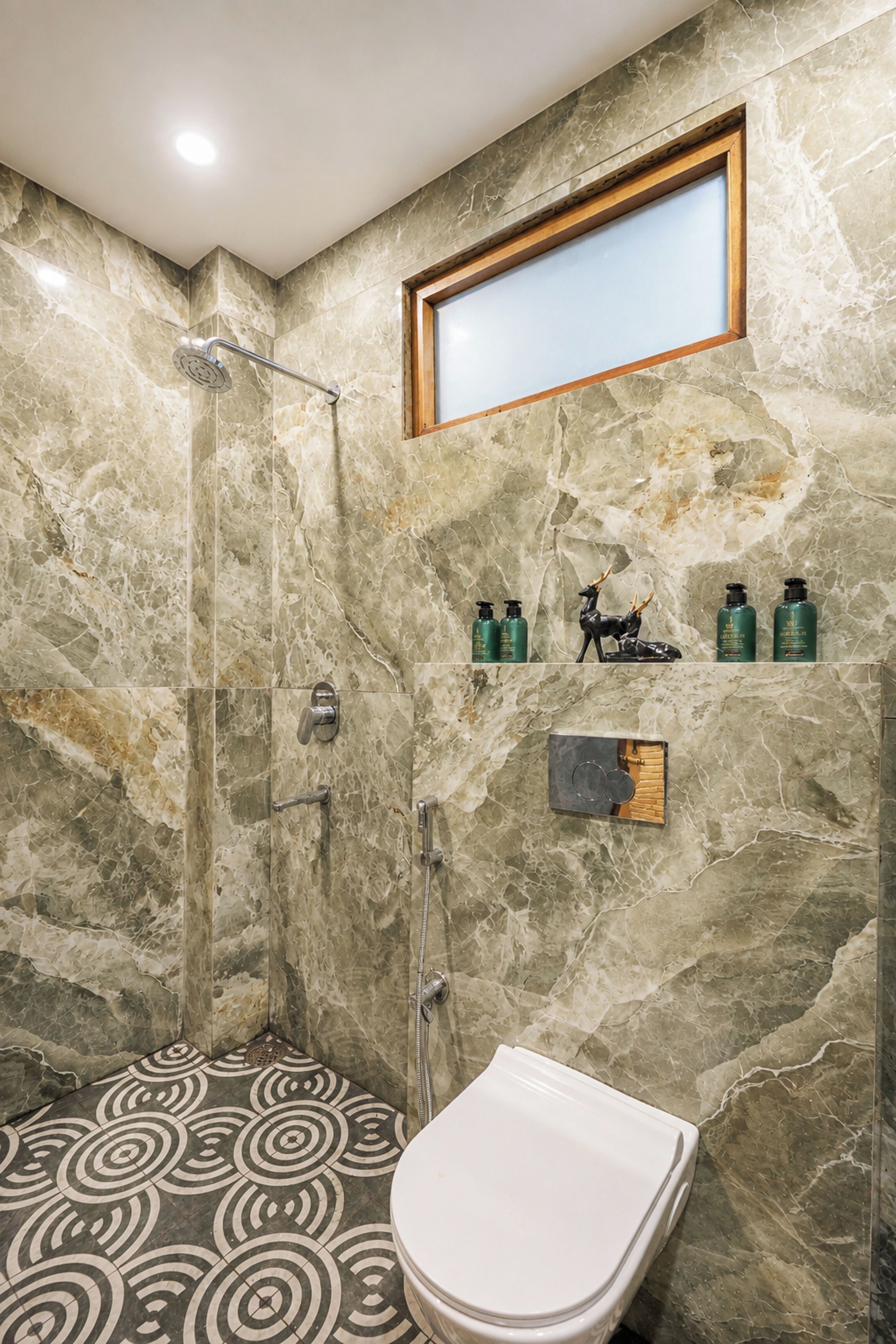 A bathroom with a shower, toilet, and marble walls.