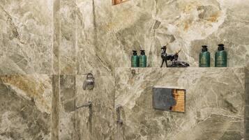 A bathroom with a shower, toilet, and marble walls.
