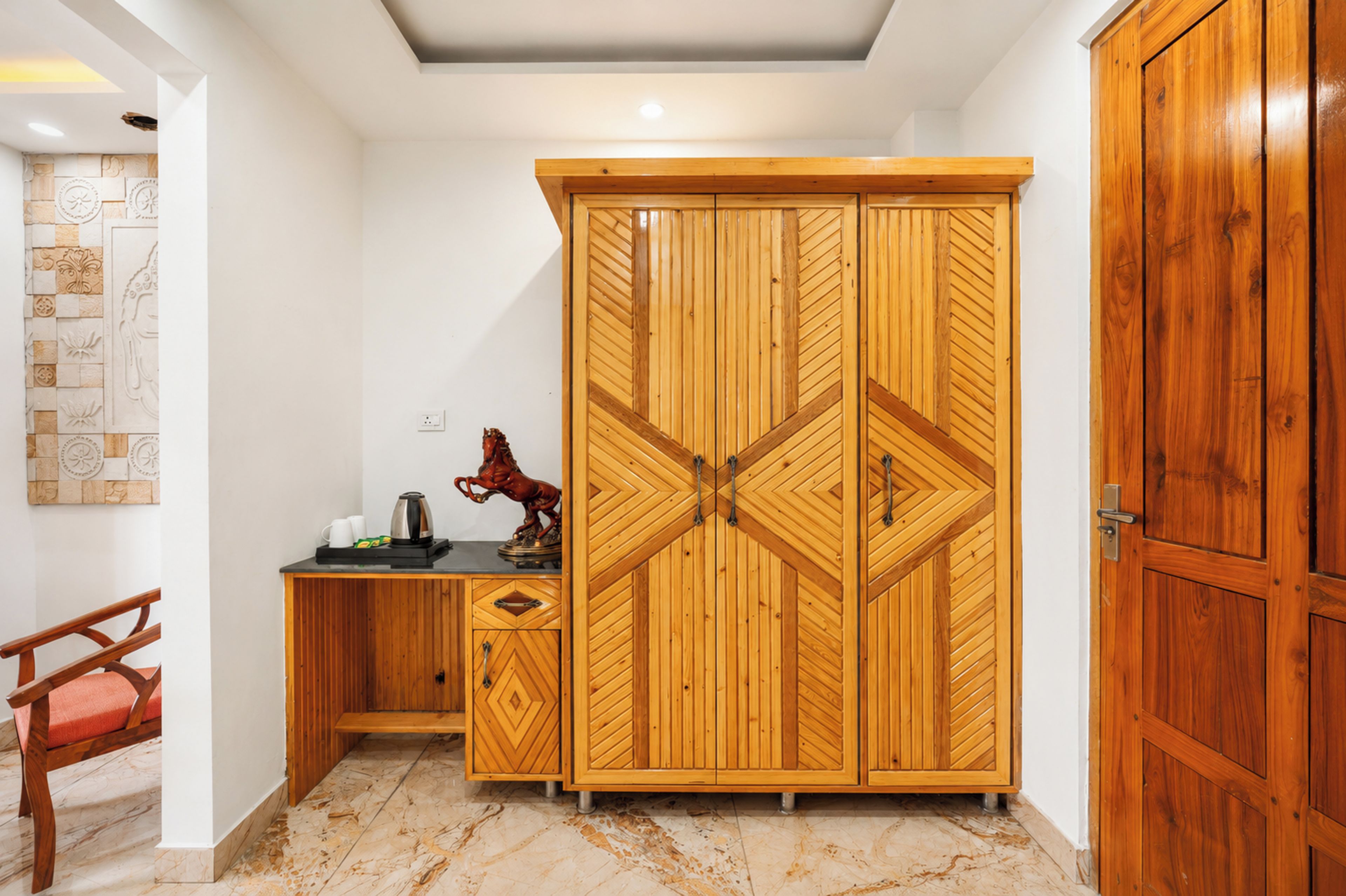 Una habitación con un armario de madera, un escritorio, una silla y una estatua decorativa de Buda.