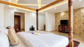 A bedroom with a four-poster bed, a television, and a patterned wallpaper.