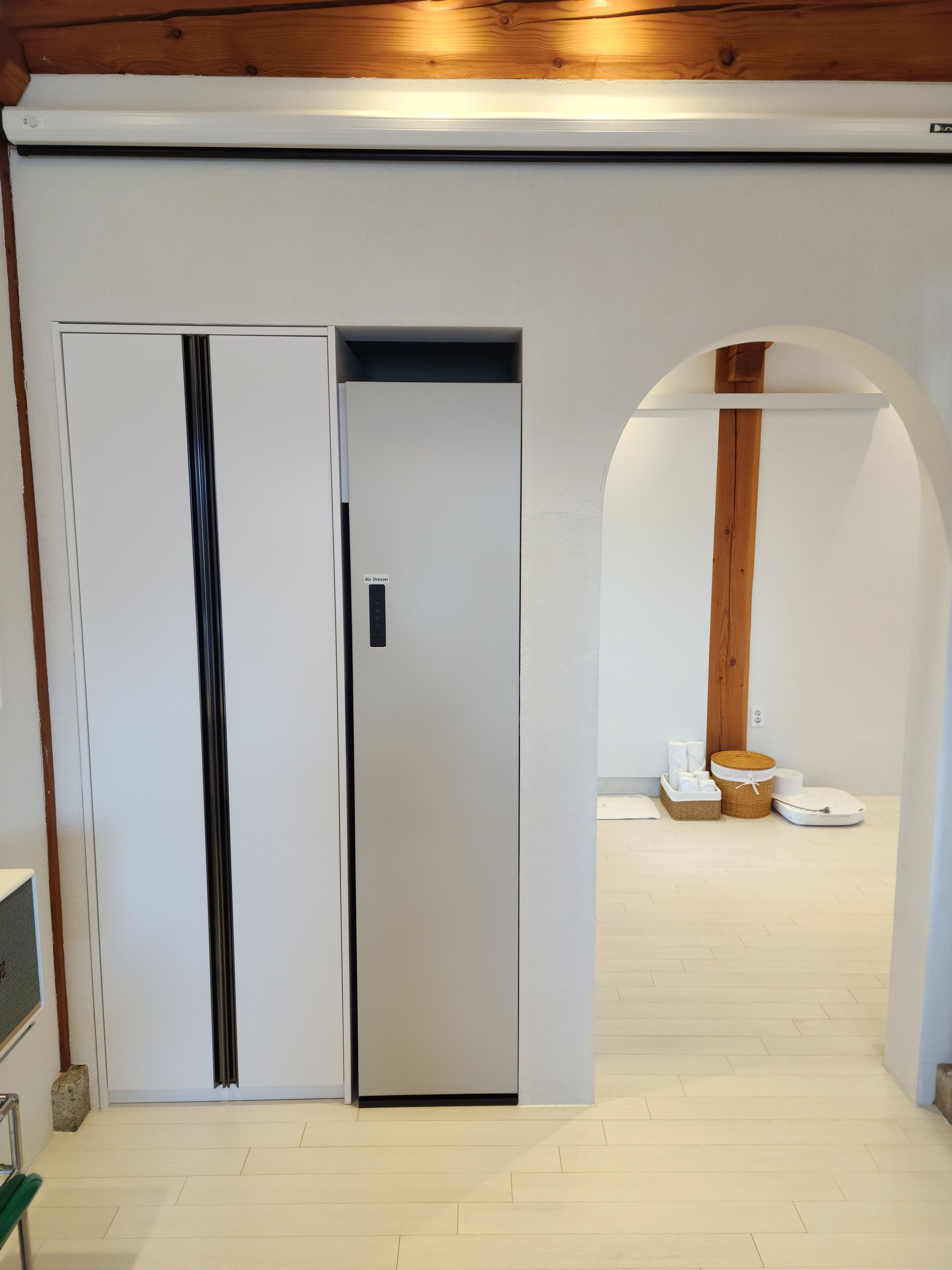 A modern interior with a white wall, a wooden ceiling, and a white floor.