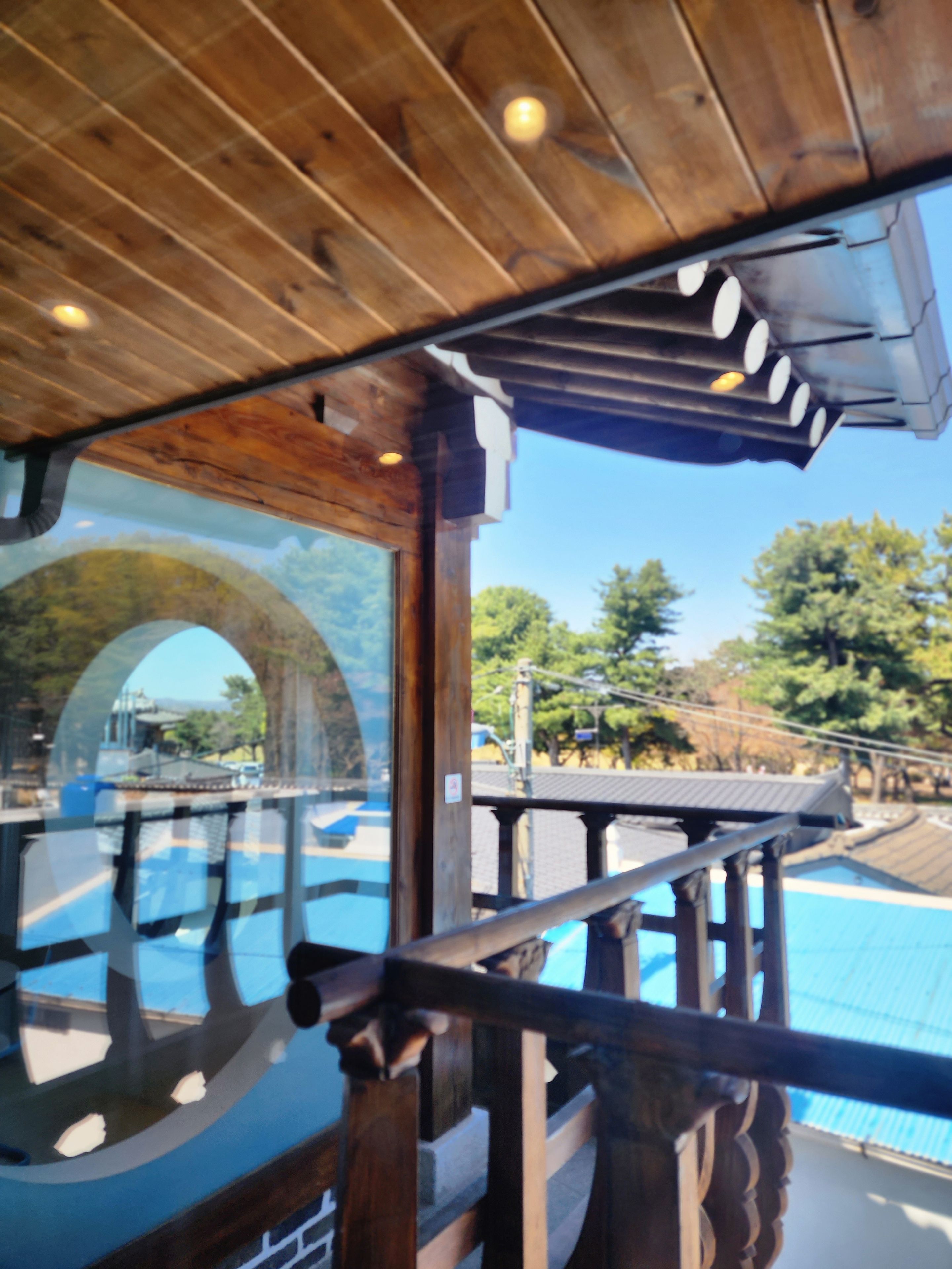 A wooden ceiling with a glass window reflecting an outdoor scene.