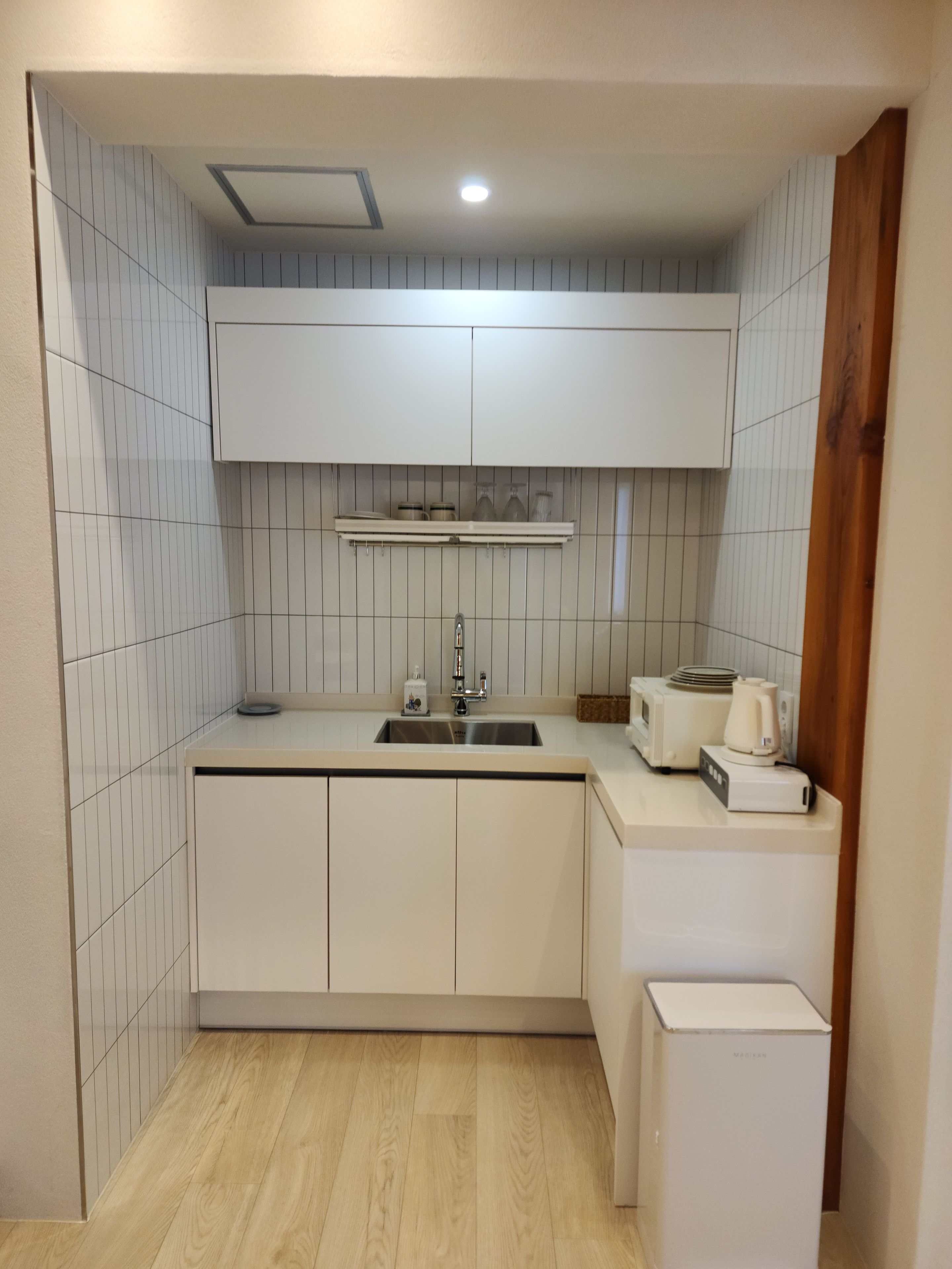 A compact kitchen with white cabinetry, a built-in sink, and a microwave.