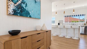 Eine moderne Küche mit einer Holzauskleidung, Barhocker und einem großen Gemälde einer Küstenlandschaft.