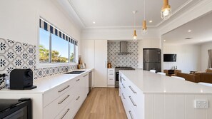 Eine moderne Küche mit einer großen Kochinsel, weißen Schränken und einem eingebauten Backofen.