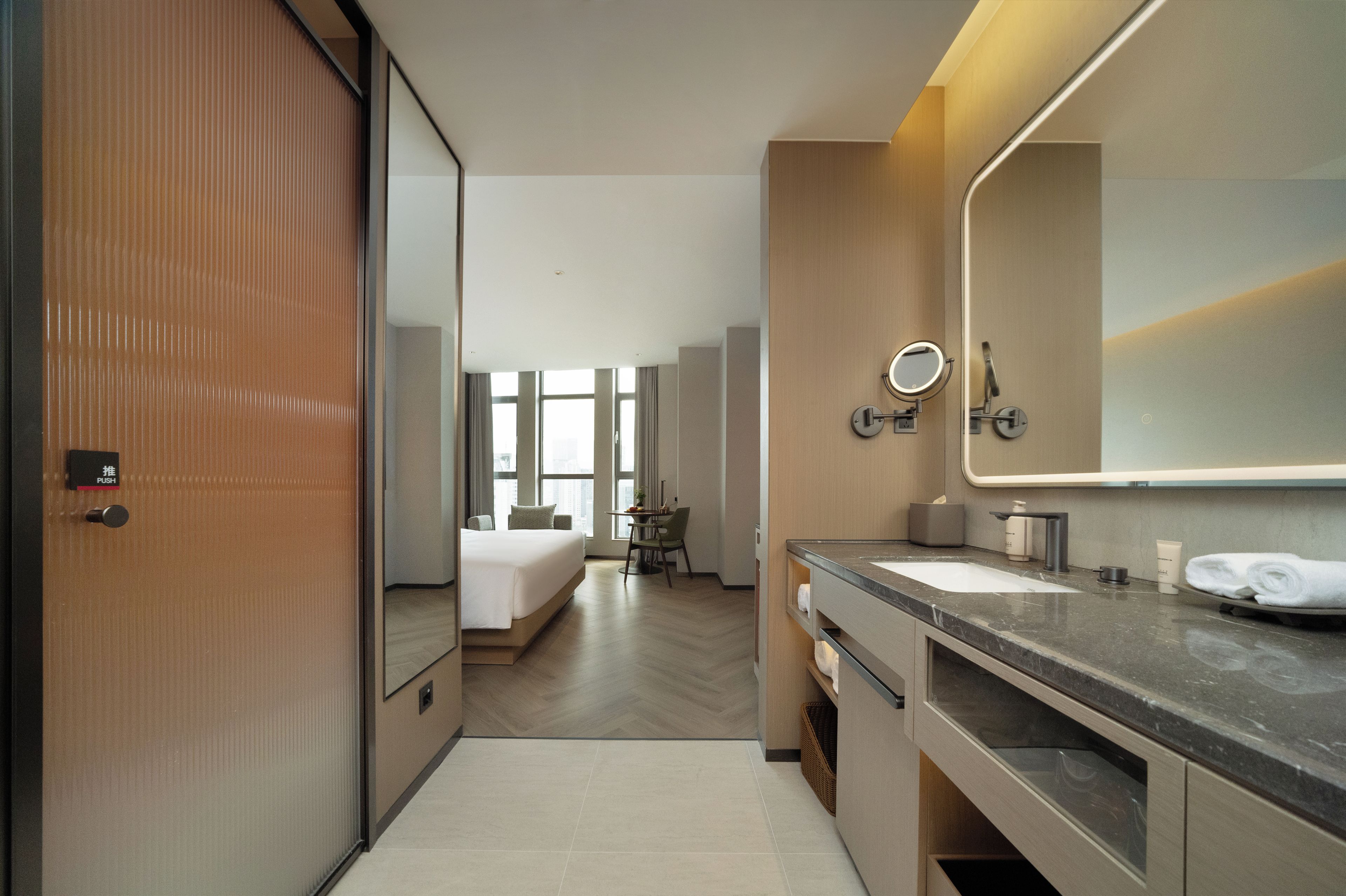 Un baño de hotel moderno con un espejo grande, un lavamanos y un inodoro.