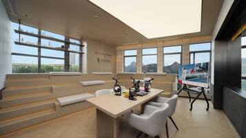 A modern conference room with a high ceiling, large windows, and a cityscape view.